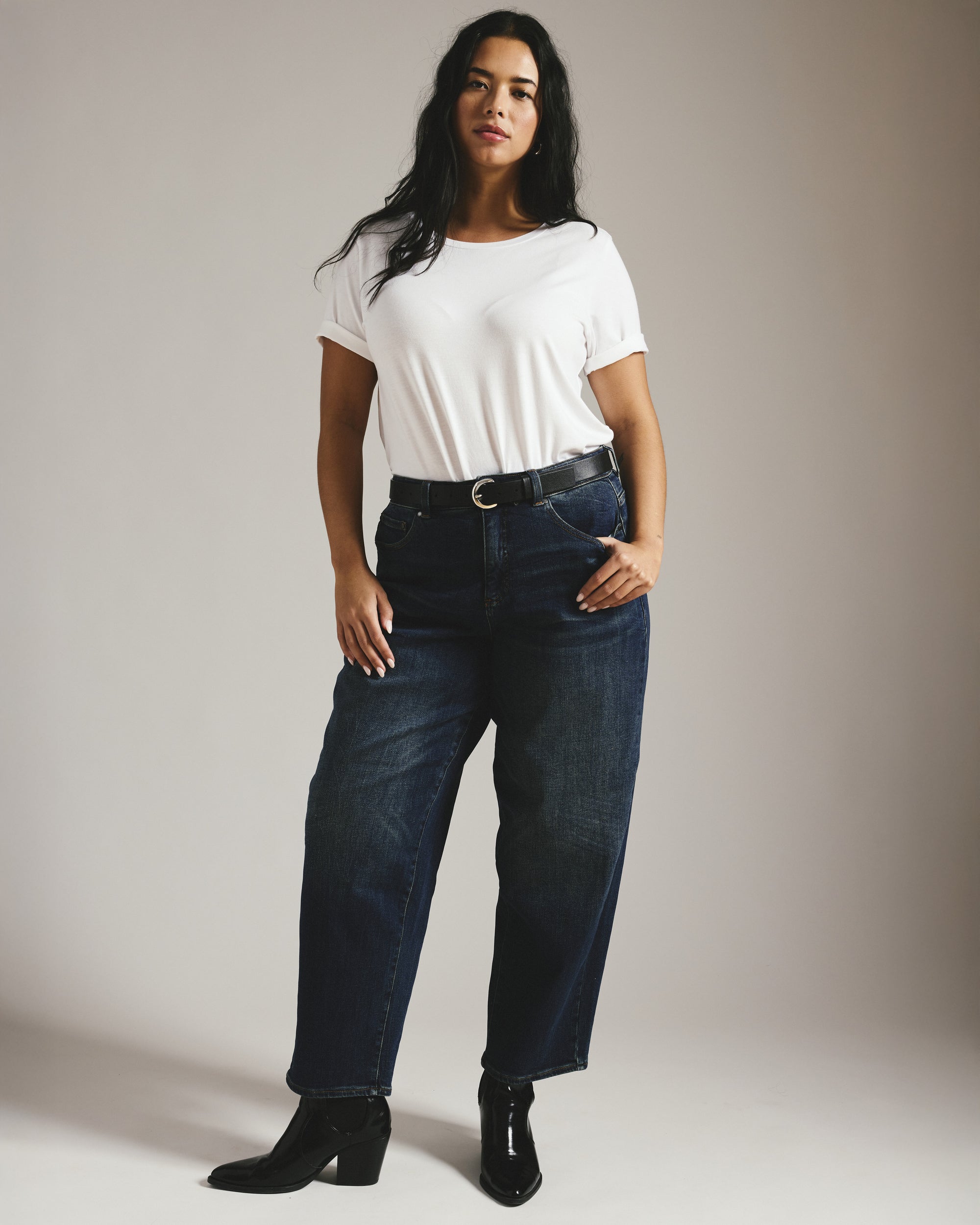 Dark indigo plus-size barrel jeans laid flat showing curved leg shape and high-rise waistband
