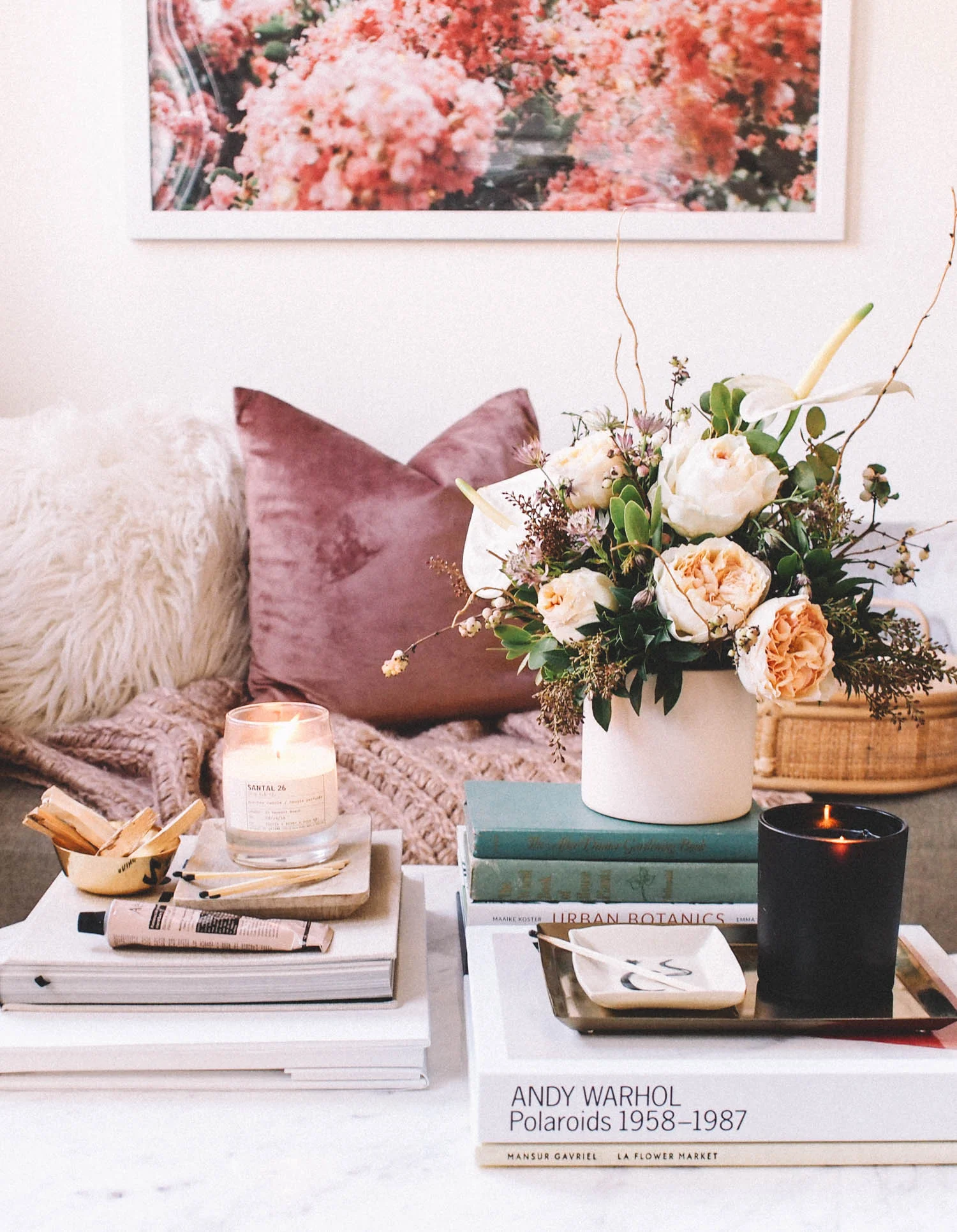 Decorative book stack display on a coffee table with candle and plant