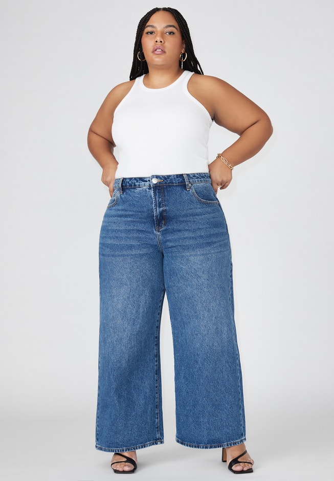 Four pairs of Eloquii jeans in different washes and cuts arranged on a wood floor
