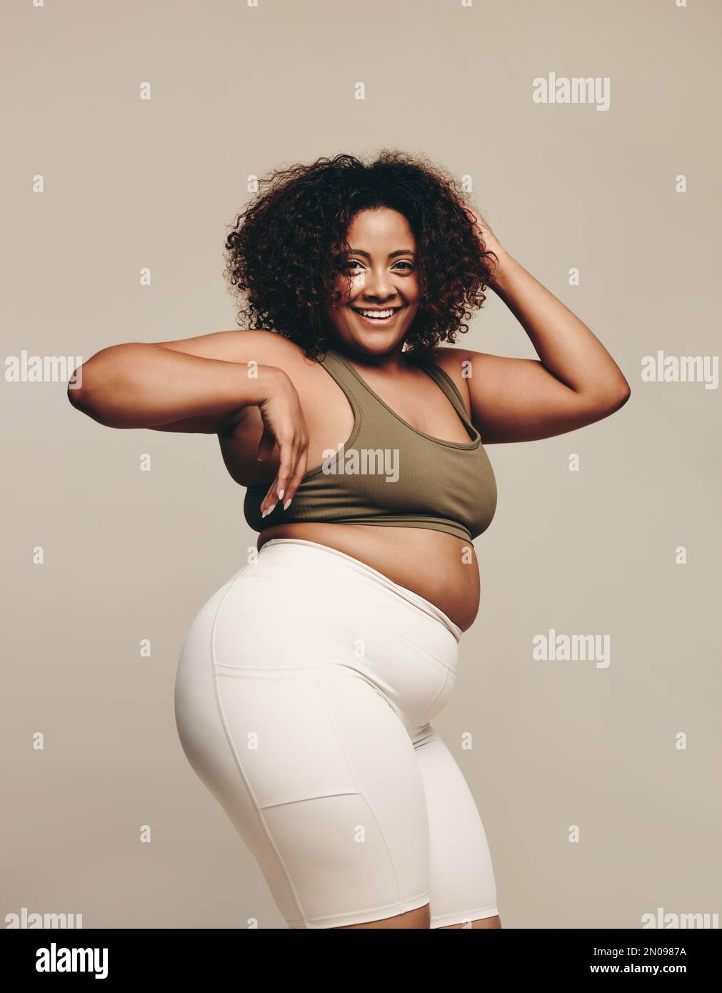 Joyful plus-size woman dancing in her living room following an online dance workout