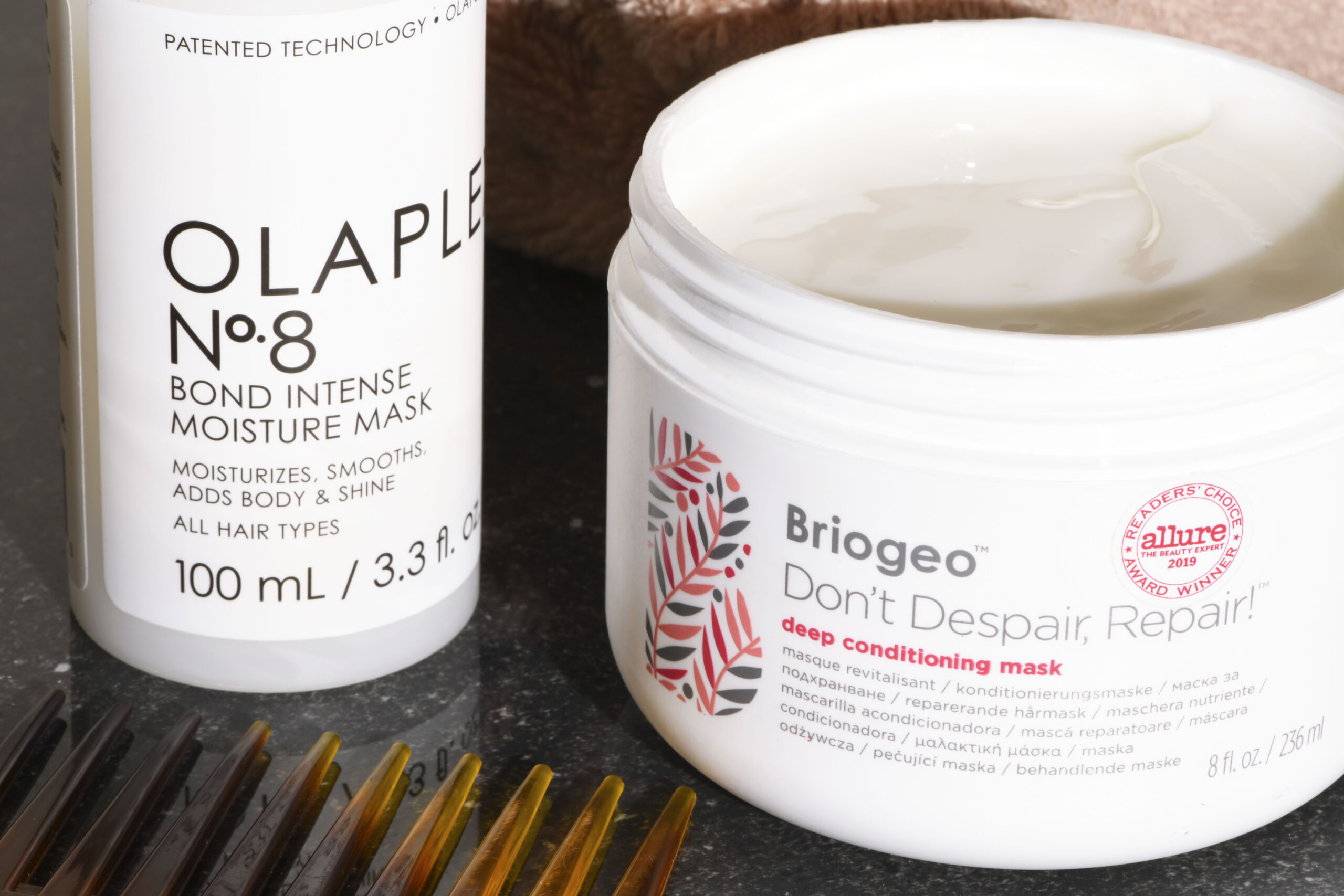 Olaplex No. 3 and Briogeo Don't Despair Repair side by side on a beige linen background