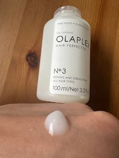 Olaplex No. 3 Hair Perfector bottle held in hand in bathroom setting