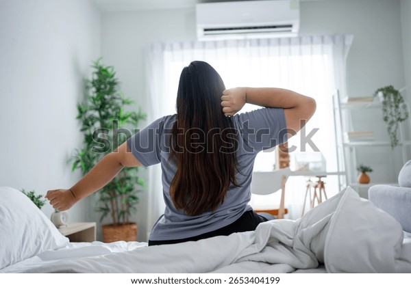 Plus-size woman doing a gentle seated stretch in her calm, cozy bedroom