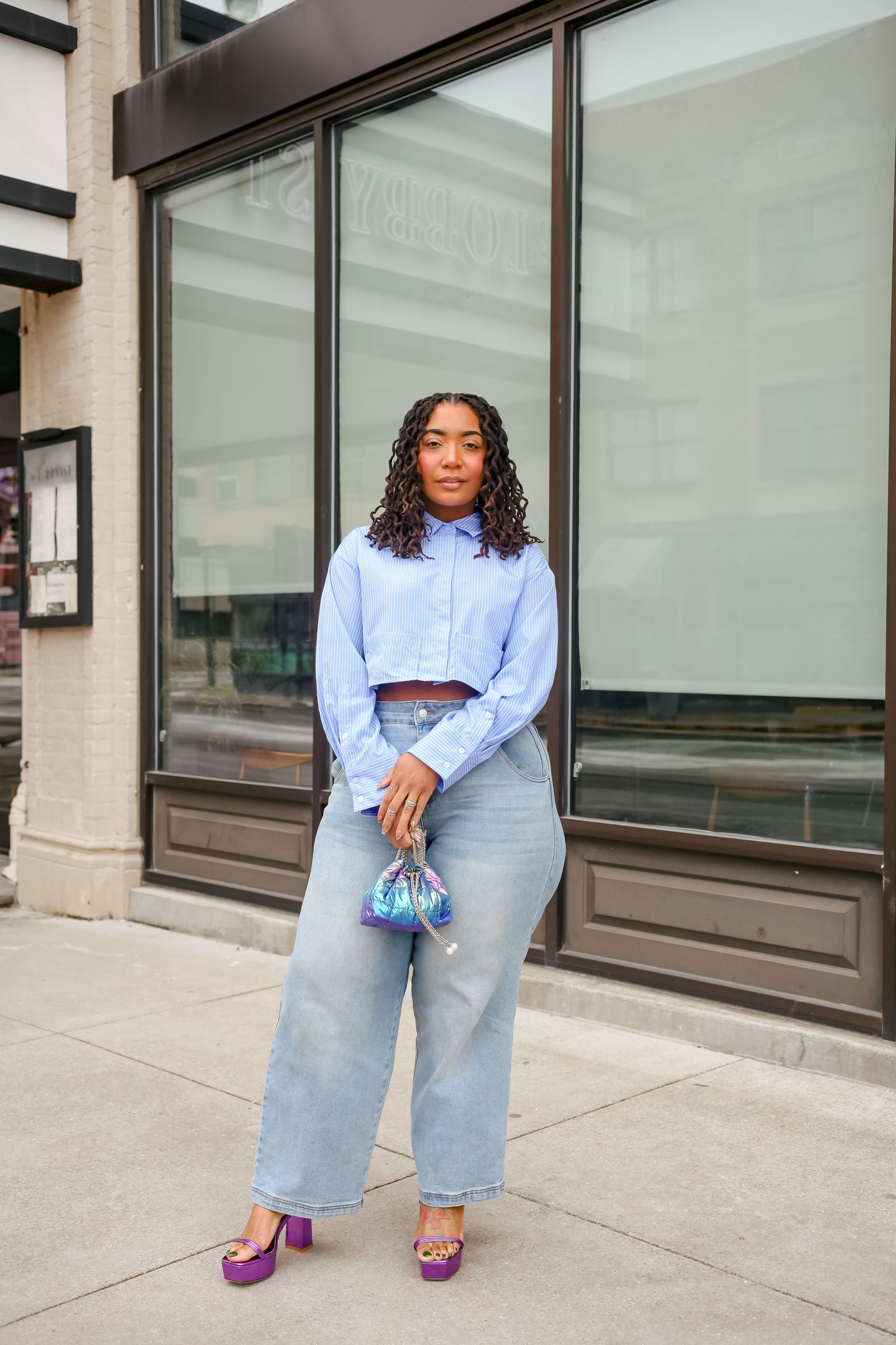Three top styles laid flat next to plus-size barrel jeans showing tucked tank, structured blazer, and cropped boxy tee