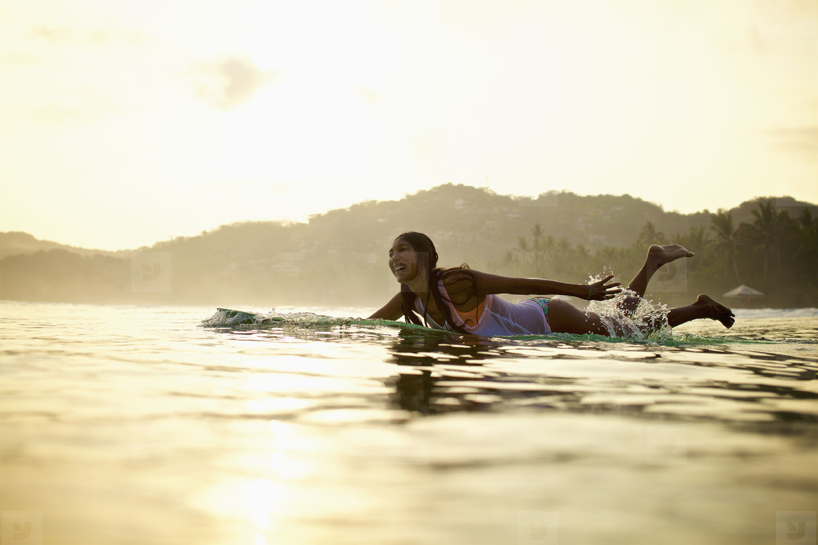 A plus-size woman surfer paddling a longboard in Sayulita Mexico wearing a properly fitted 4/3 wetsuit