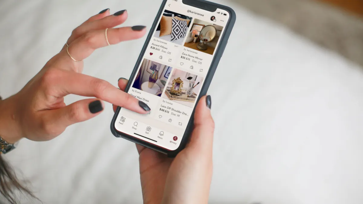 Hands holding an iPhone showing a Poshmark plus-size dress listing in a closet view with the actual garment photographed in the background