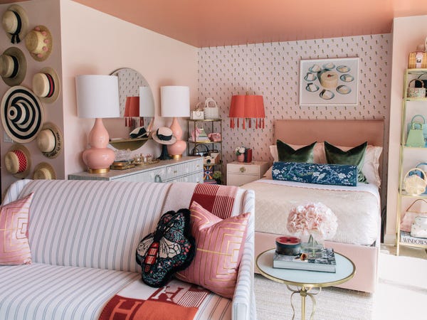 A plus-size woman seated on a made bed reviewing a notebook with the 5-phase 47-minute Sunday closet protocol while the prepared lineup of five outfits hangs in the closet behind her