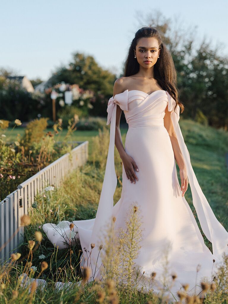A dusty rose chiffon bridesmaid dress with off-the-shoulder neckline on a curved dress form