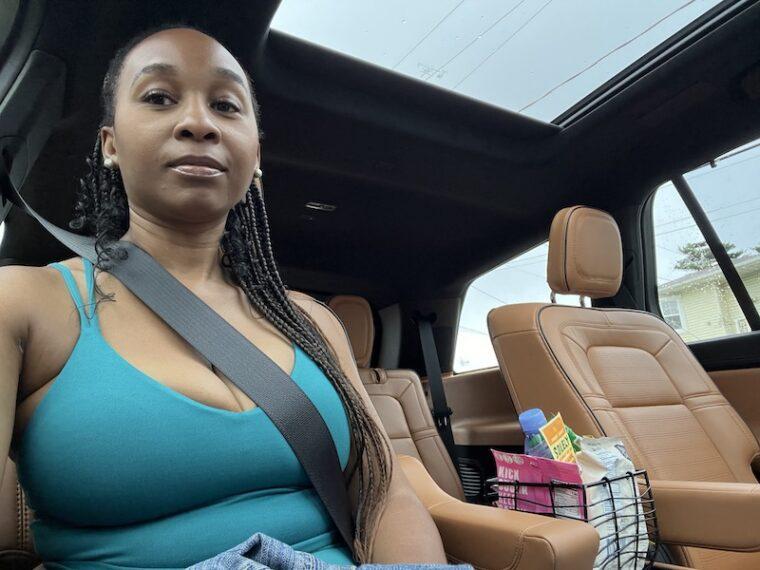 Plus-size Black woman riding comfortably in a car on a sunlit highway