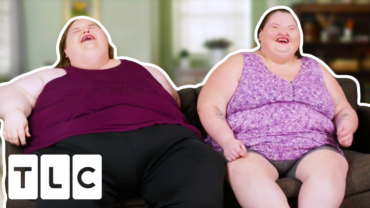 Two plus-size women sisters laughing together at a coastal overlook on a road trip