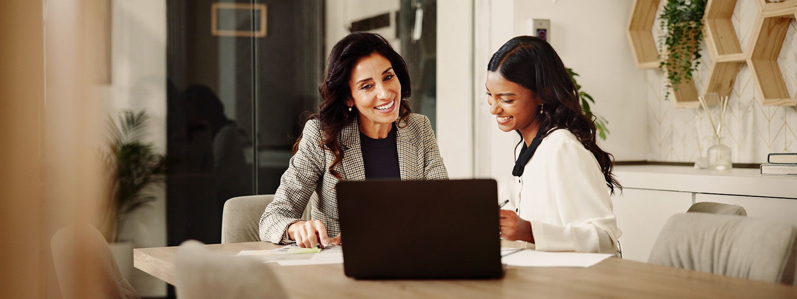 Two women in business attire seated across conference table reviewing single sheet of paper