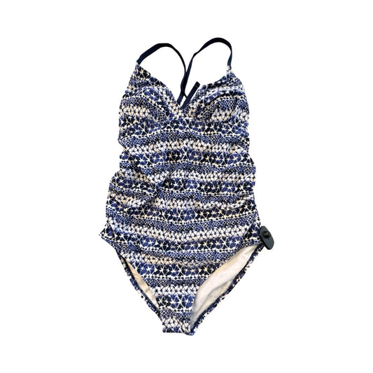 Swim designer Renée Hill pinning a navy one-piece on a dress form in a sunlit Brooklyn studio, pattern paper and fabric swatches on the worktable behind her