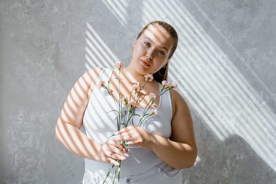 A plus-size woman smoothing a dress over a shaping bodysuit, looking confident