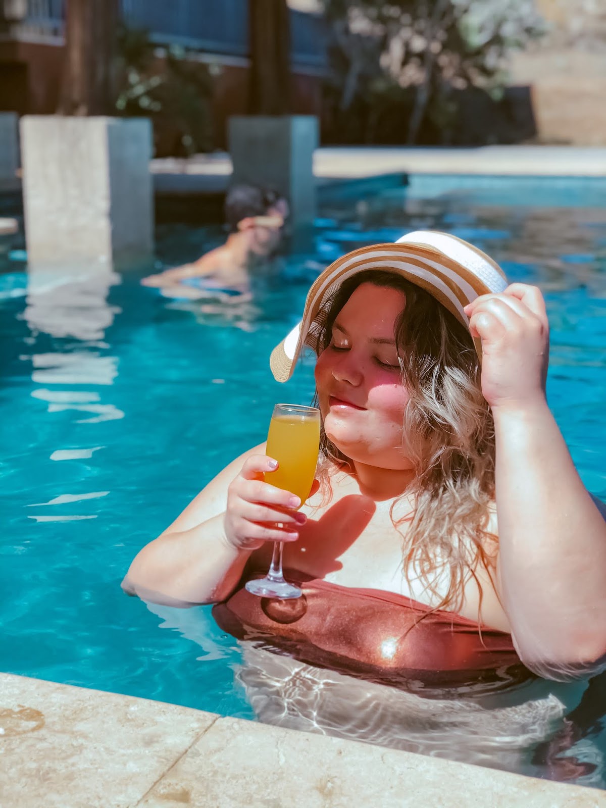 Plus-size woman enjoying tropical cocktail on beautiful resort beach