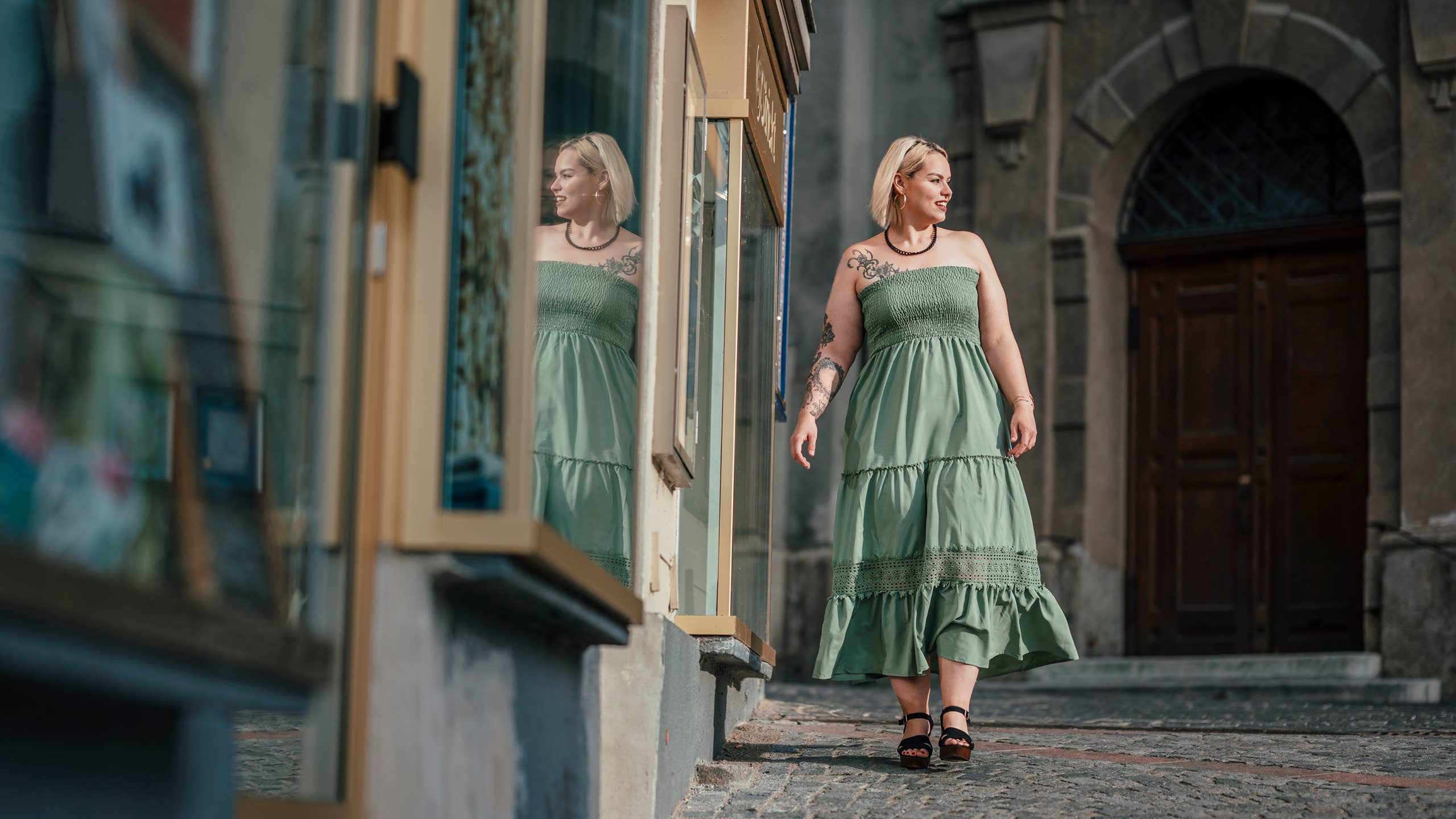 Plus-size woman walking confidently through outdoor market in flowing dress