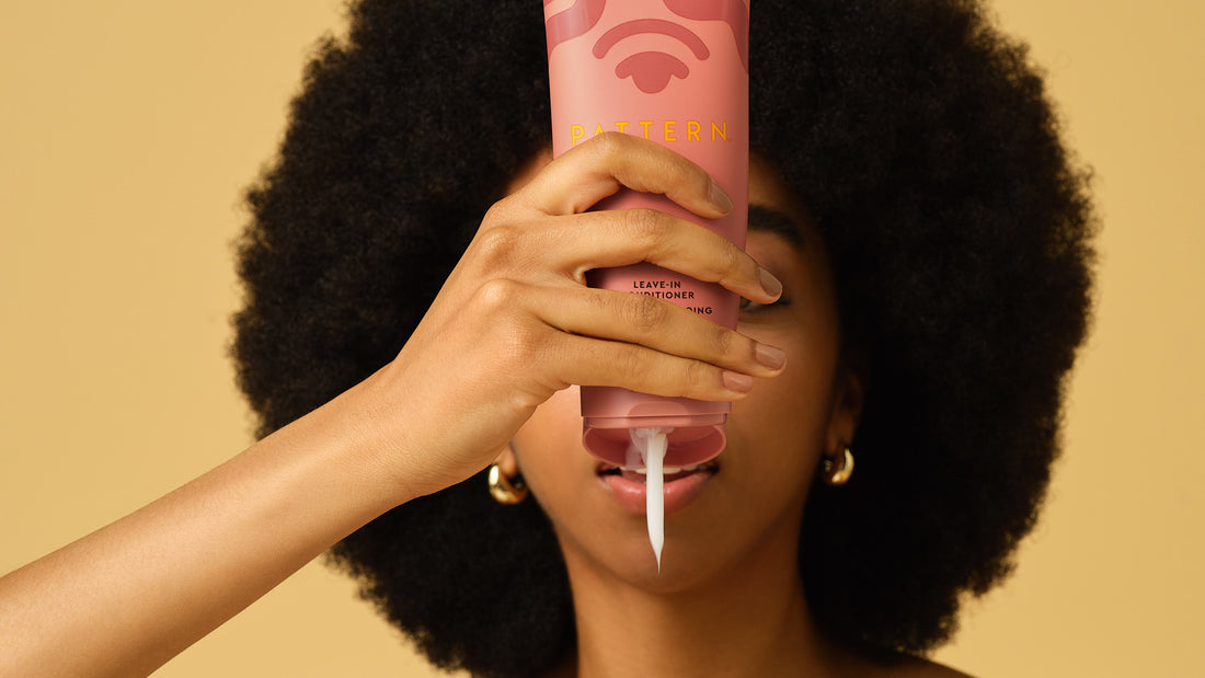 Woman applying leave-in conditioner to sectioned 4C hair in bathroom