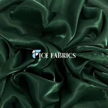 Close up of emerald satin and dusty rose chiffon fabric swatches side by side