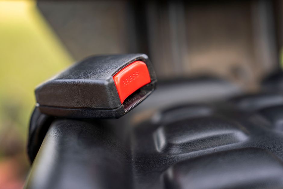 Close view of a car seatbelt buckle and latch plate in a vehicle interior
