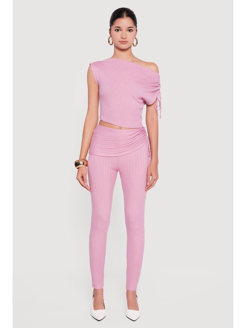 Folded ribbed knit tops and leggings stacked on a bed