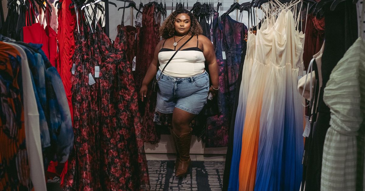 Plus size shopper browsing a rack of denim in a bright clothing store