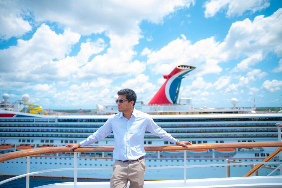 Plus size woman in a bright dress standing at a cruise ship railing at sunset