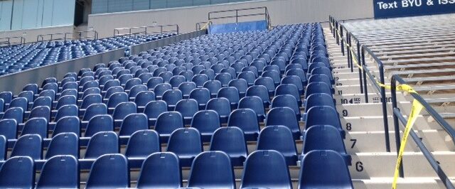 Rows of empty stadium seats with fixed armrests between each seat