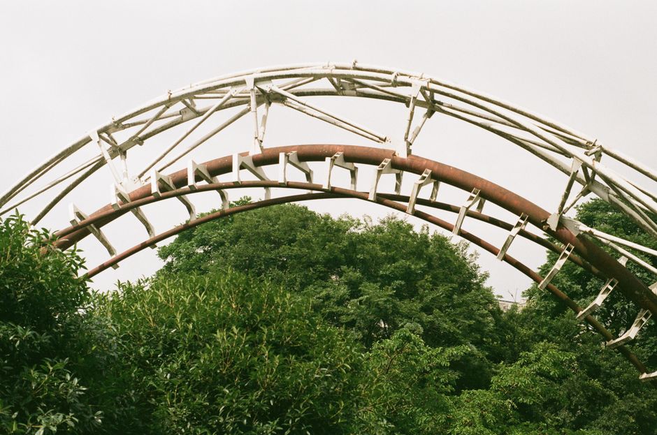 Steel roller coaster track curving above a theme park walkway